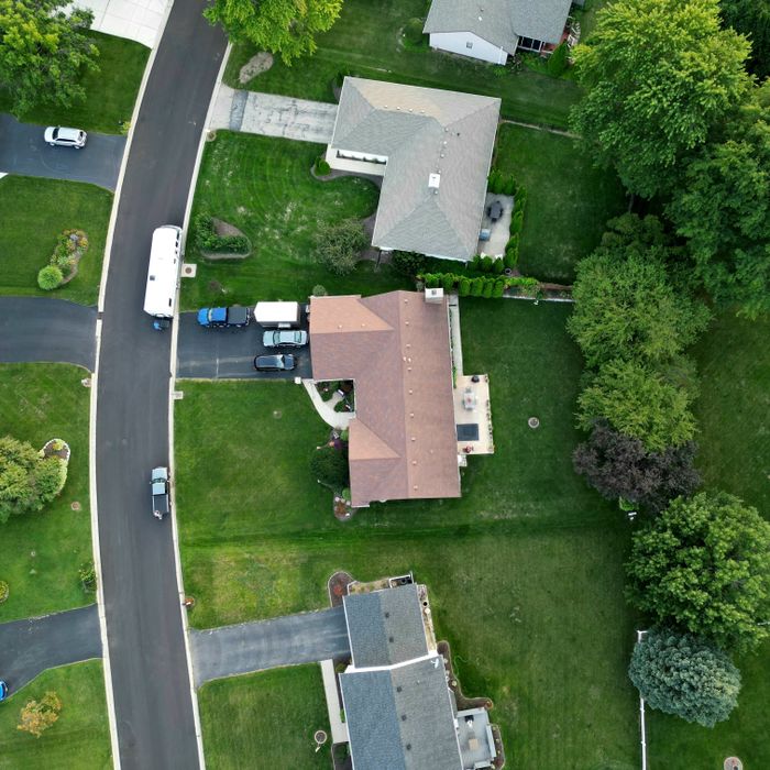 Aerial view of a suburban neighborhood showcasing houses, roads and lush greenery.