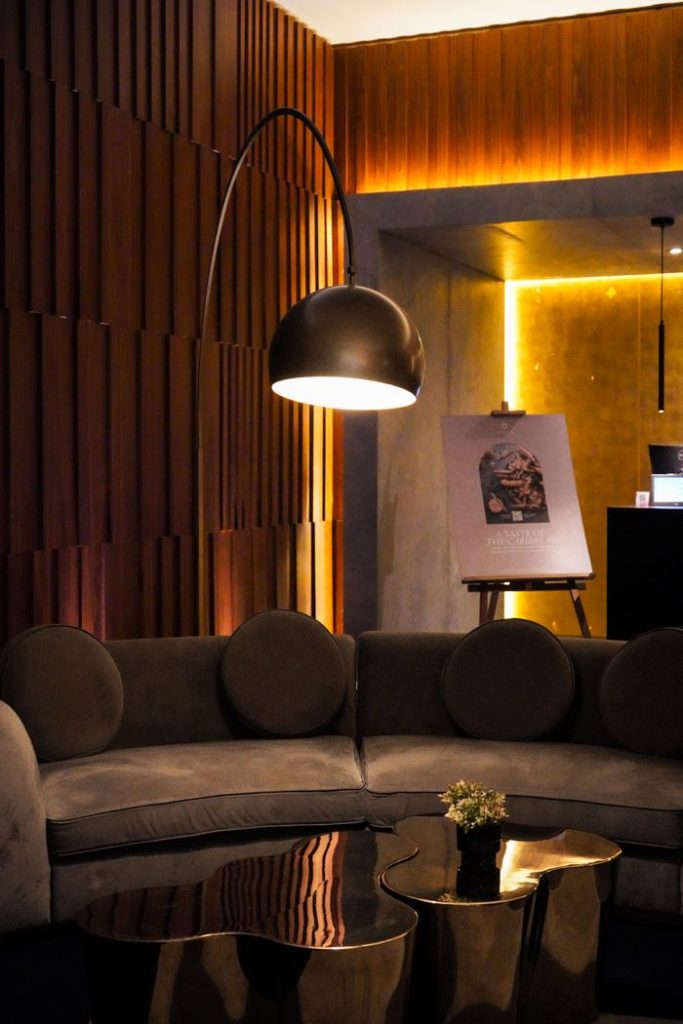 Warmly lit modern lounge with stylish curved sofa and standing lamp, ideal for relaxation.